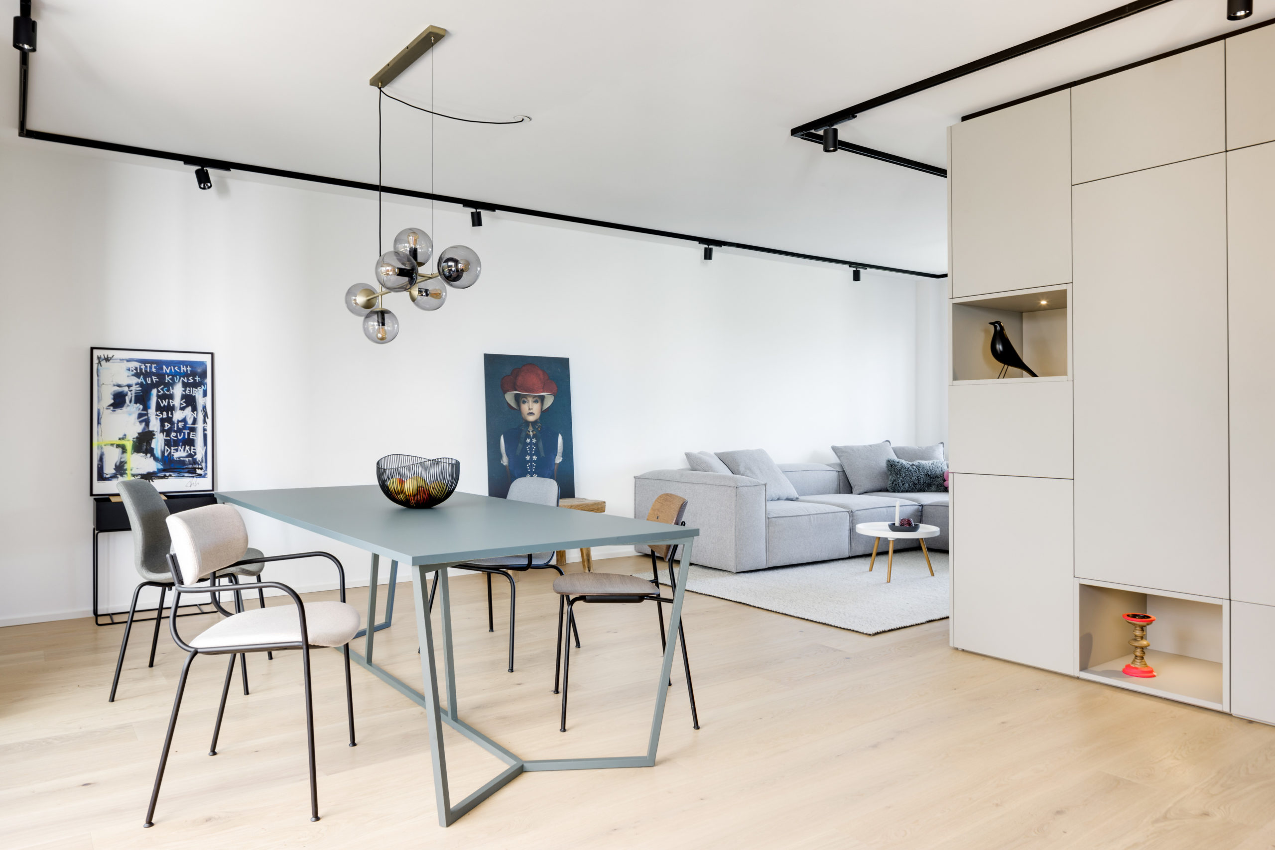 Offener Essbereich mit Wohnzimmerschrank, Design-Esstisch und grauem Modulsofa