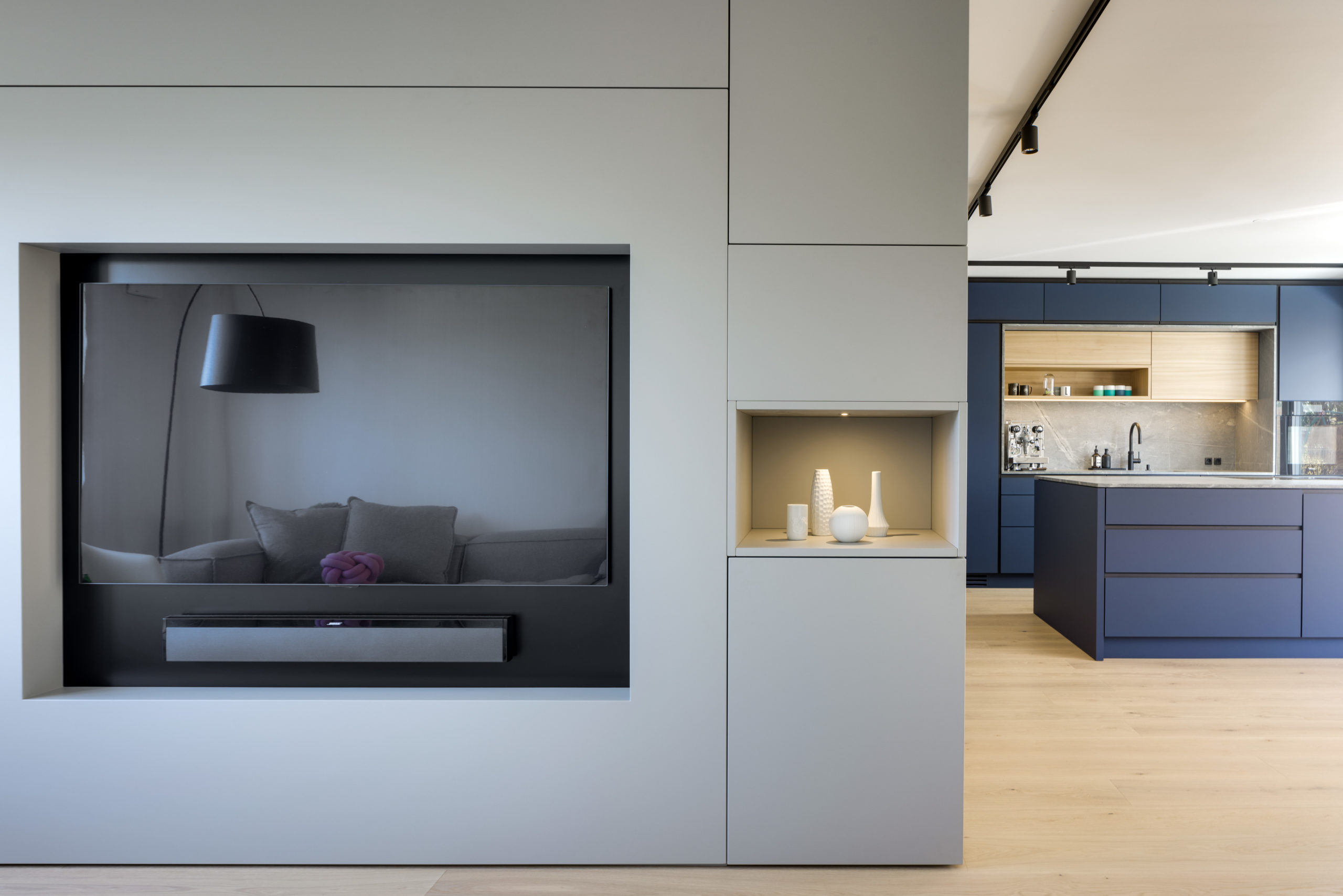 Offene Wohnküche mit TV-Einbauwand, blauen Küchenfronten und Interior Design Details