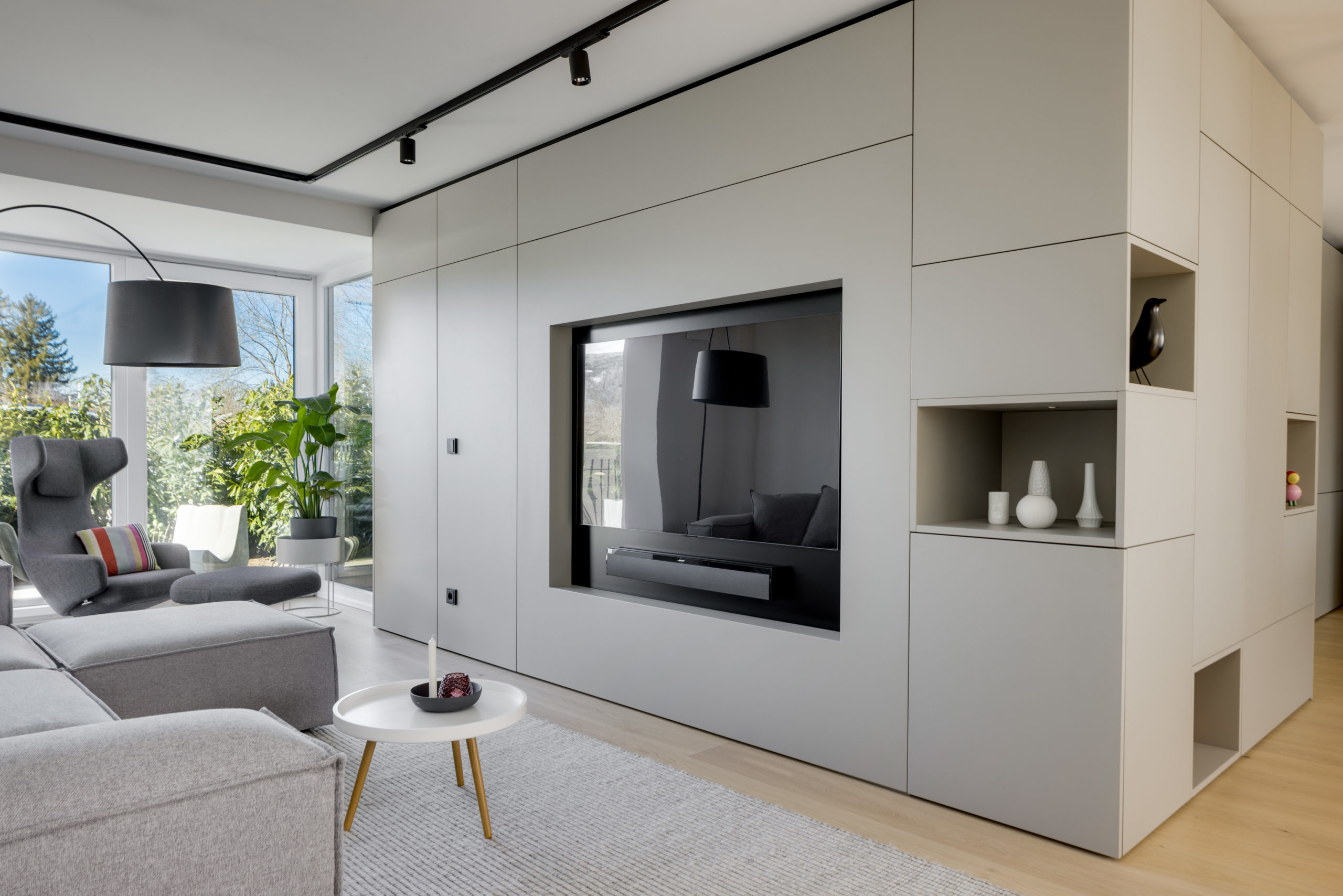 Wohnzimmer mit TV-Einbaumöbel, grauem Sofa und raumhohen Einbauten