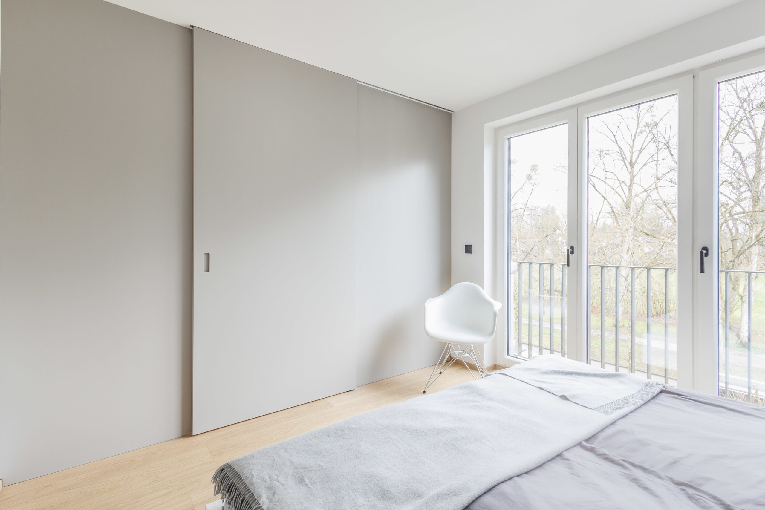 Ankleidezimmer mit geschlossener, raumhoher Schiebetür im minimalistischen Design