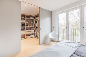 Ankleidezimmer, raumhoher Einbauschränke mit Schubladen und Kleiderstange im minimalistischen Design