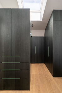 ankleidezimmer-mit-dunklen-holzfronten-und-glasgriffen