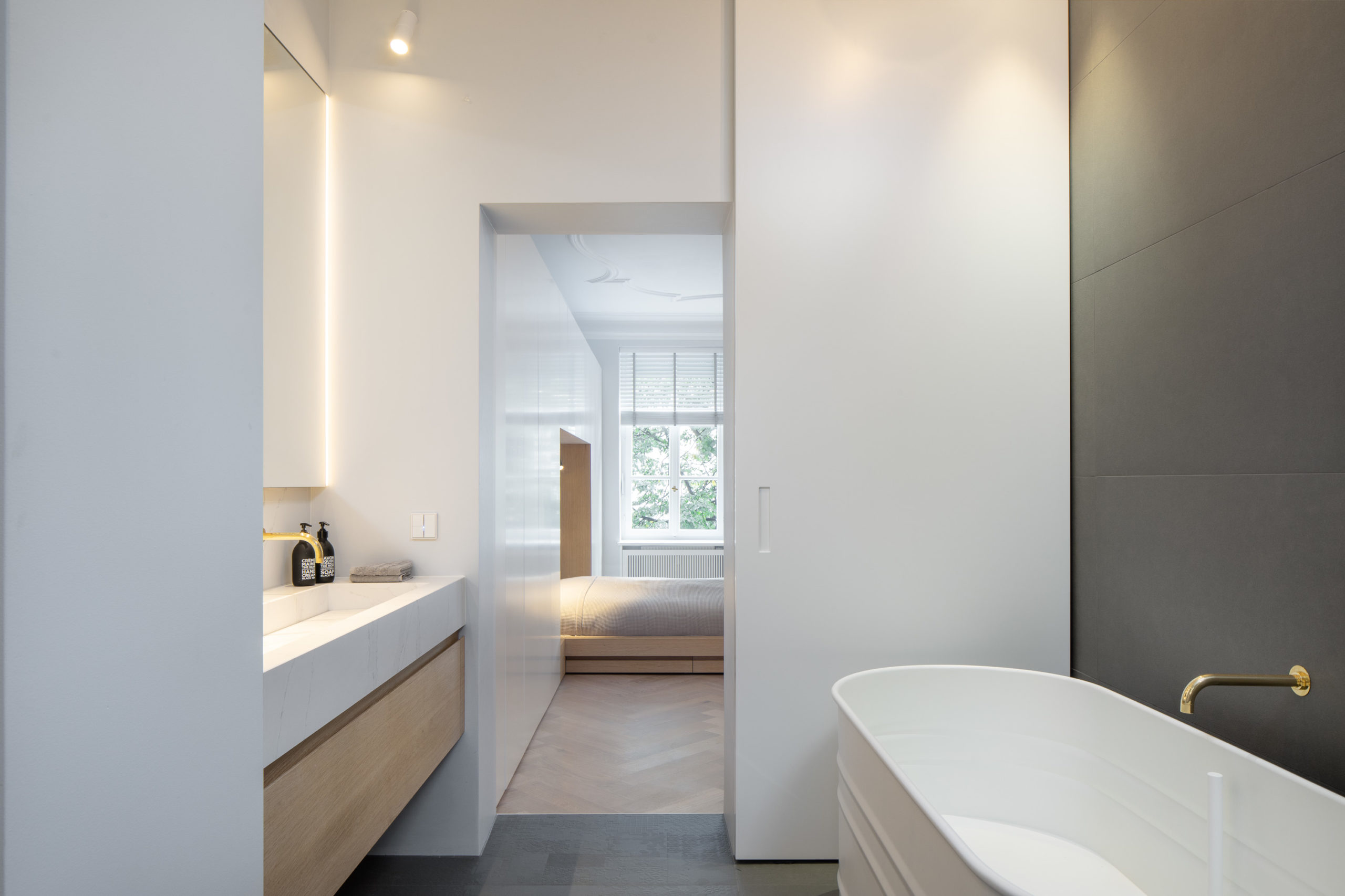 Helles Badezimmer mit freistehender Badewanne und Schiebetür zum Schlafzimmer