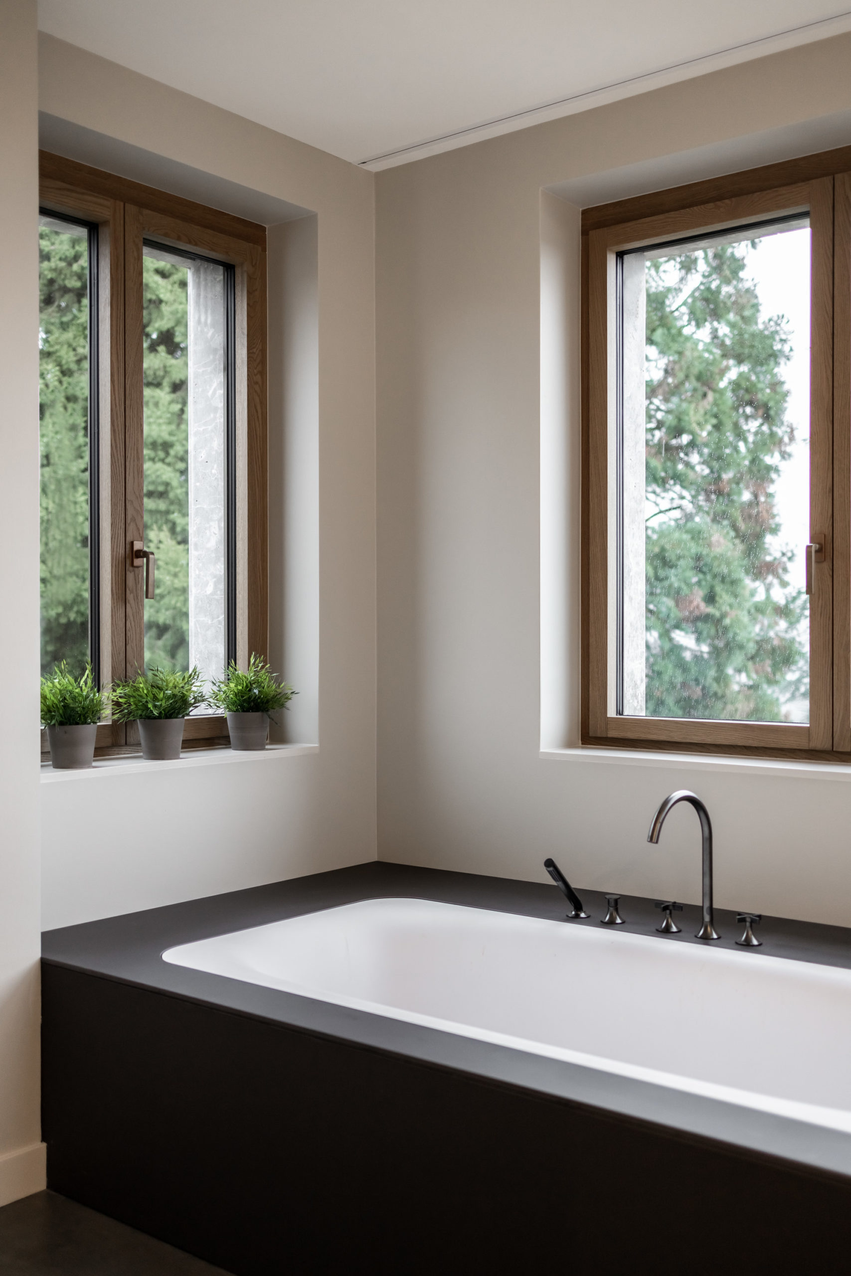 Badezimmer mit eingelassener Badewanne, großen Fenstern und Blick ins Grüne