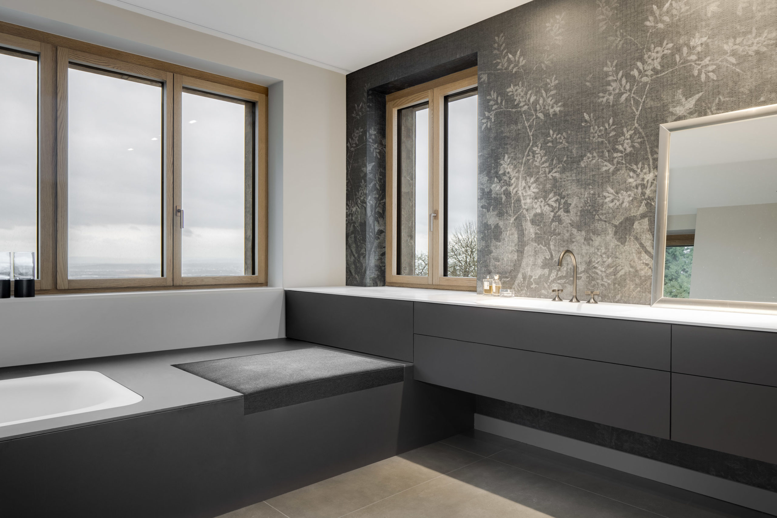 Stilvolles Badezimmer mit eingelassener Badewanne, Doppelwaschtisch und Fensterfront