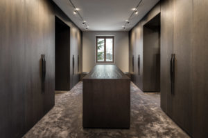 Luxuriöser begehbarer Kleiderschrank mit Mittelinsel und dunklen Holzfronten