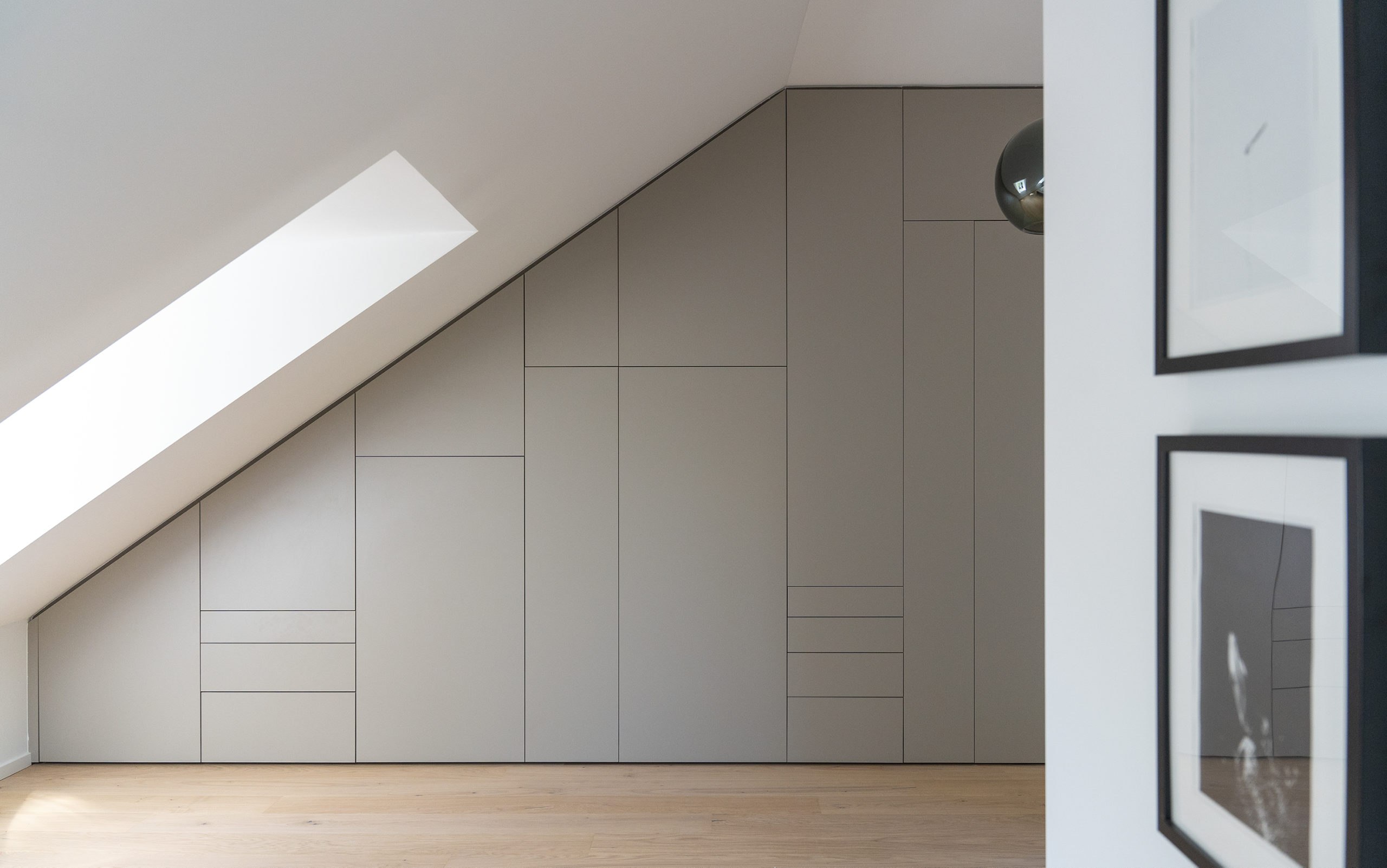 Maßgefertigter Einbauschrank unter Dachschräge in Schwabing mit klarer Linienführung und perfektem Fugenbild