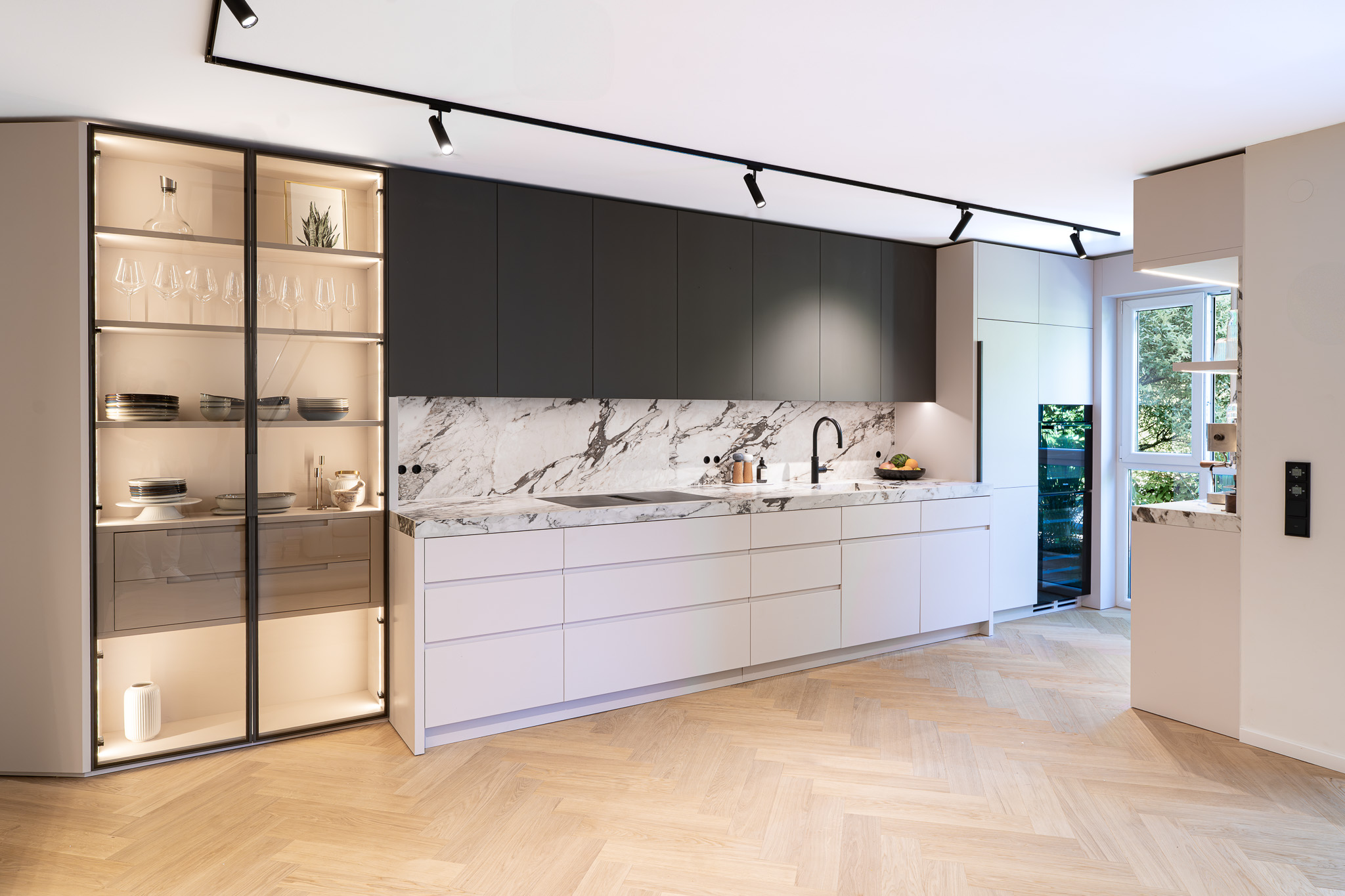 Designküche mit durchgehender Marmor-Arbeitsplatte und schwarzer Armatur, Küchenarchitektur München