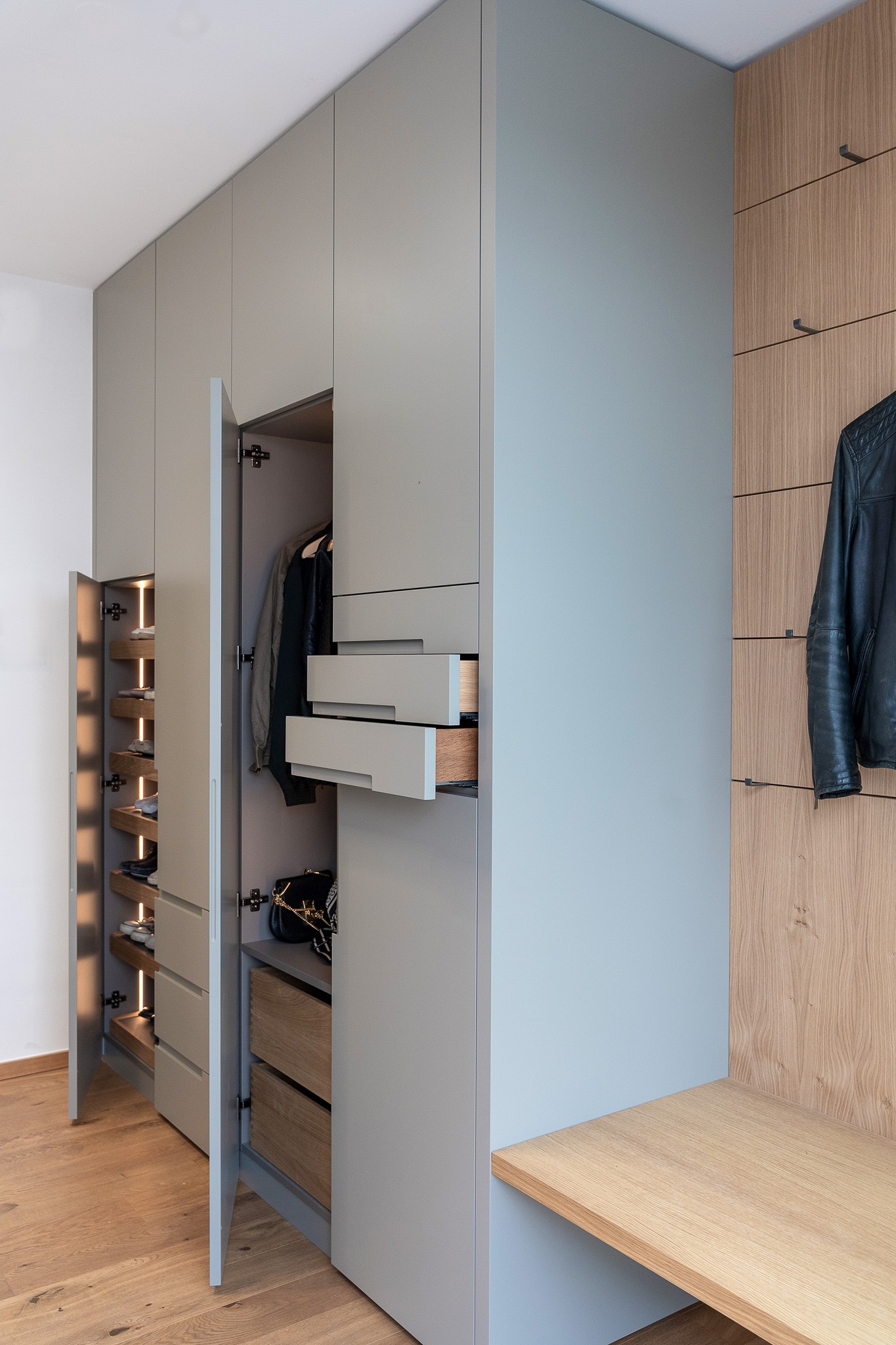 Garderoben-Einbauschrank mit ausziehbaren Tablaren und Schubladen in Obermenzing, mit klarer Linienführung und integrierter Beleuchtung.