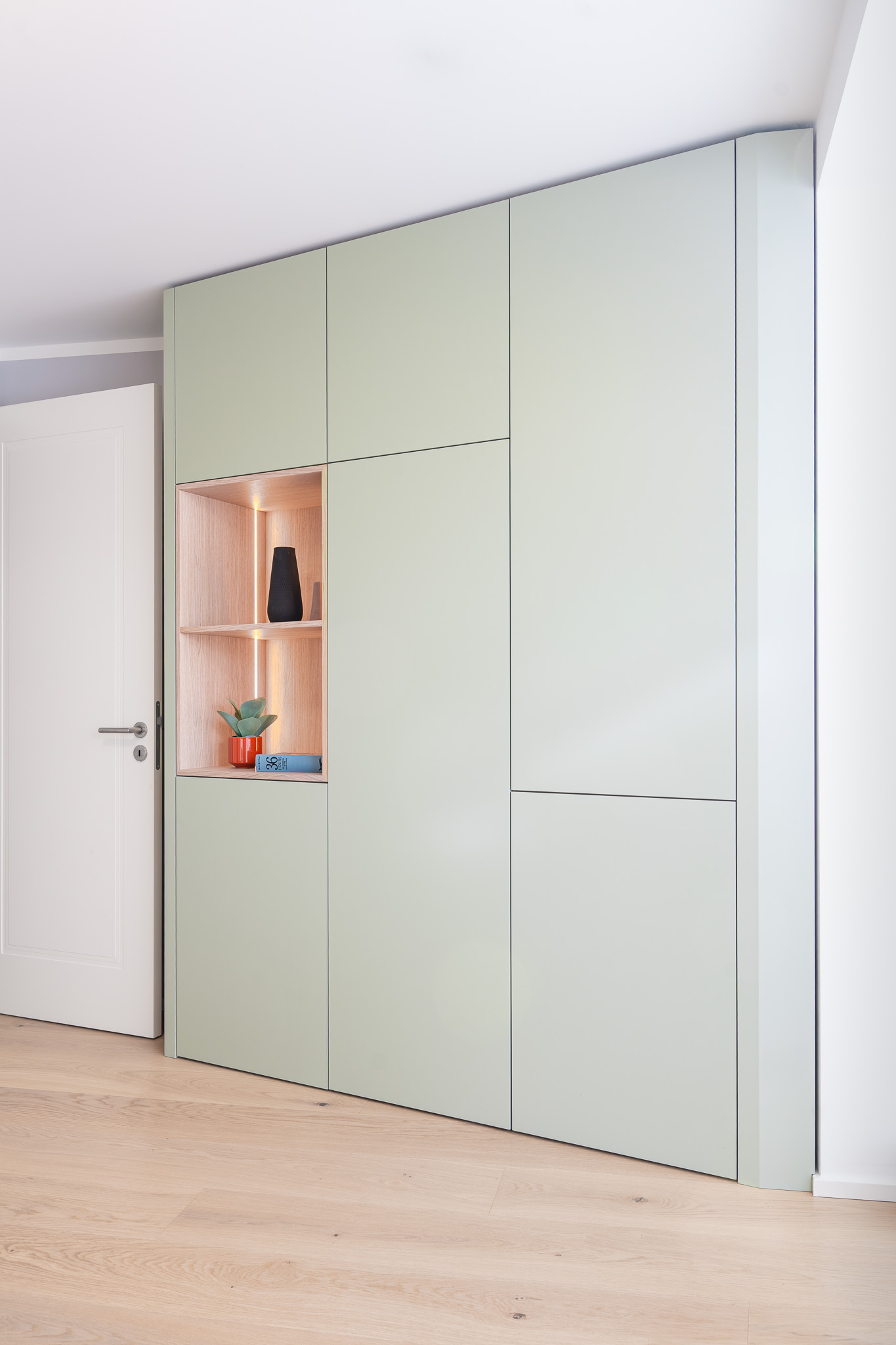 Moderner Einbauschrank in Mintgrün mit integrierter Holz-Nische und LED-Beleuchtung