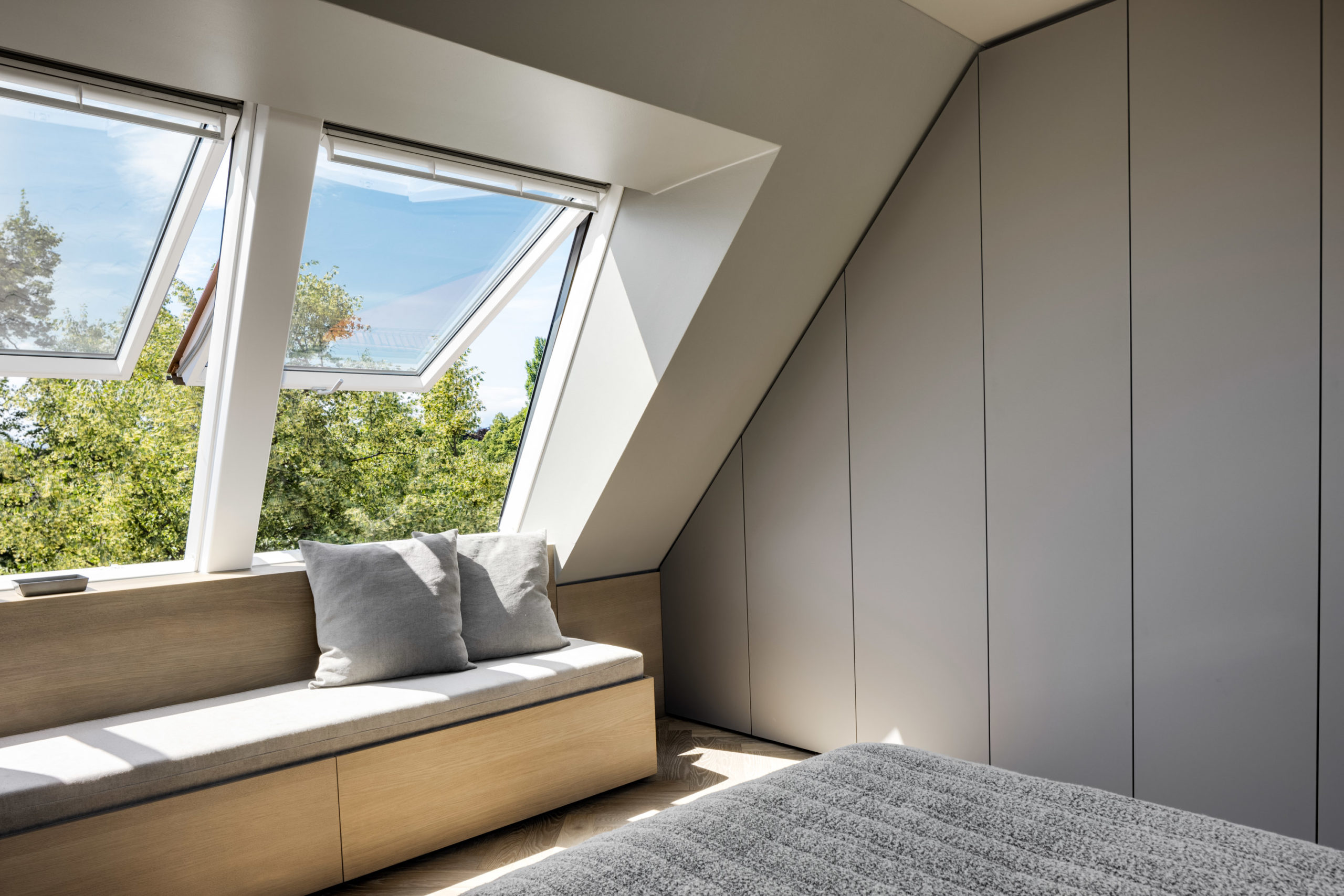 Sitzbank unter Dachfenster im hellen Dachgeschoss-Schlafzimmer