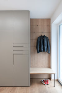 Modernes Garderobenelement mit Sitzbank und Kleiderhaken auf Eiche-Rückwand, minimalistisch gestaltet für den Eingangsbereich.