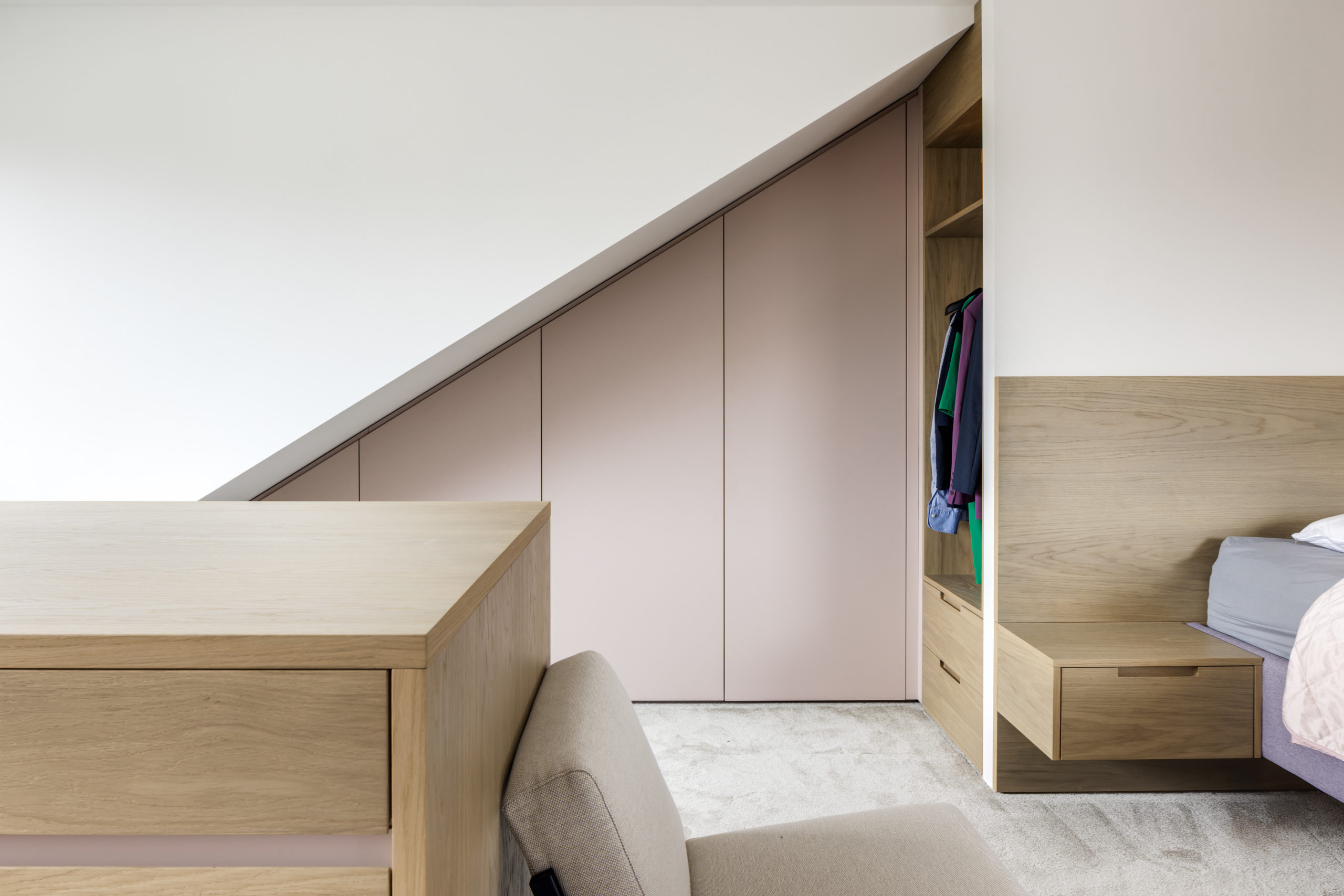 Maßgefertigter Dachschrägenschrank mit integriertem Bettkopfteil und Ankleideblock aus Eichefurnier