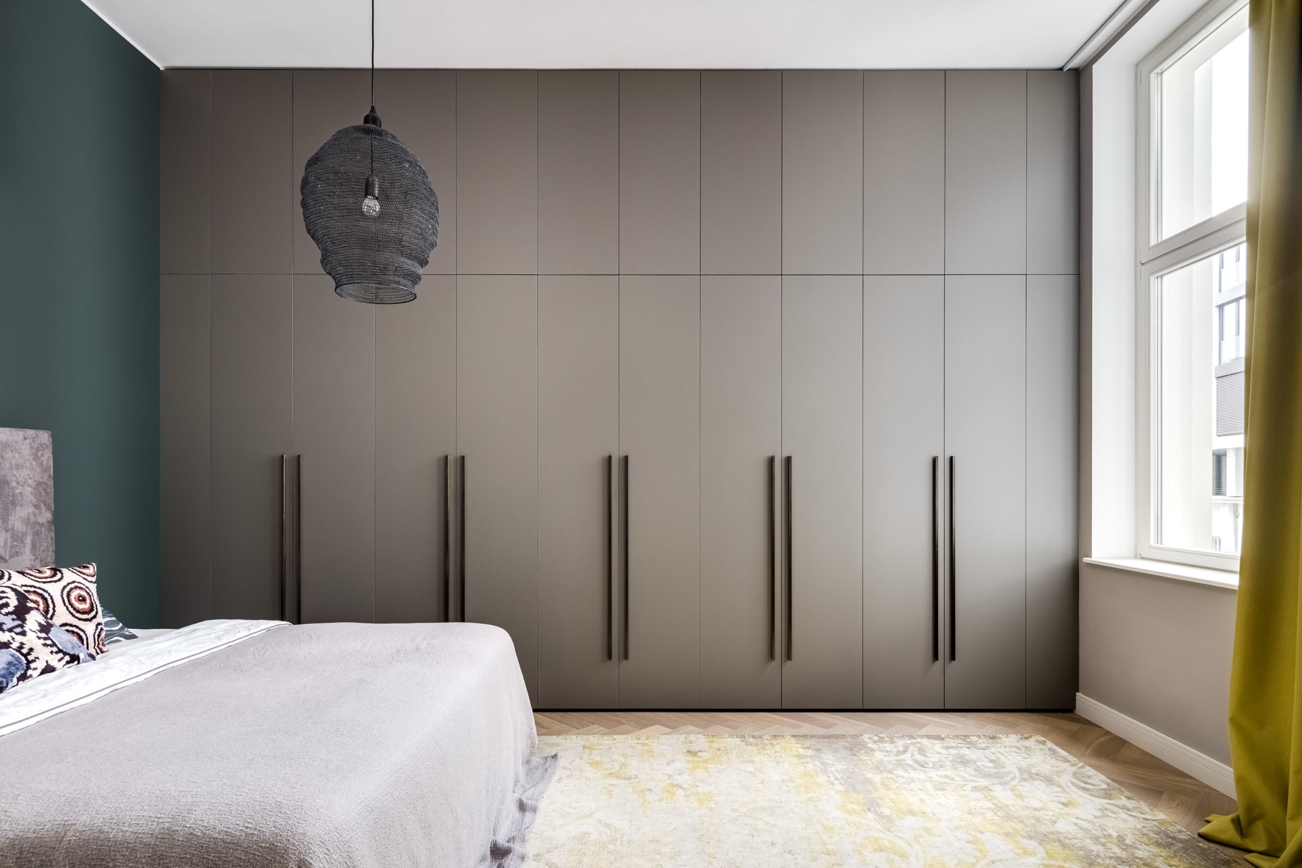 Kleiderschrank mit matten Fenix-Fronten und eleganten Messinggriffen im modernen Schlafzimmer.