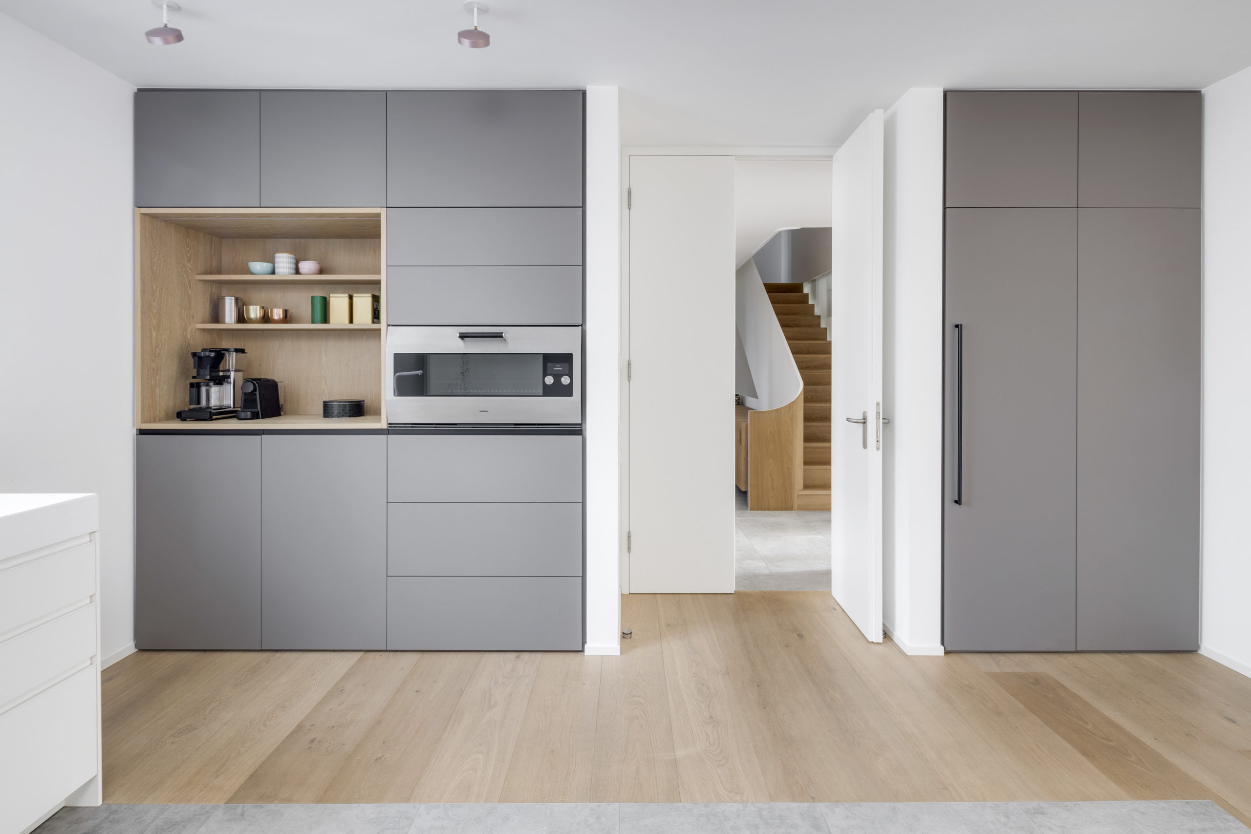 Moderne Küche mit grauen Fronten, integrierter Holznische und Hochschrank
