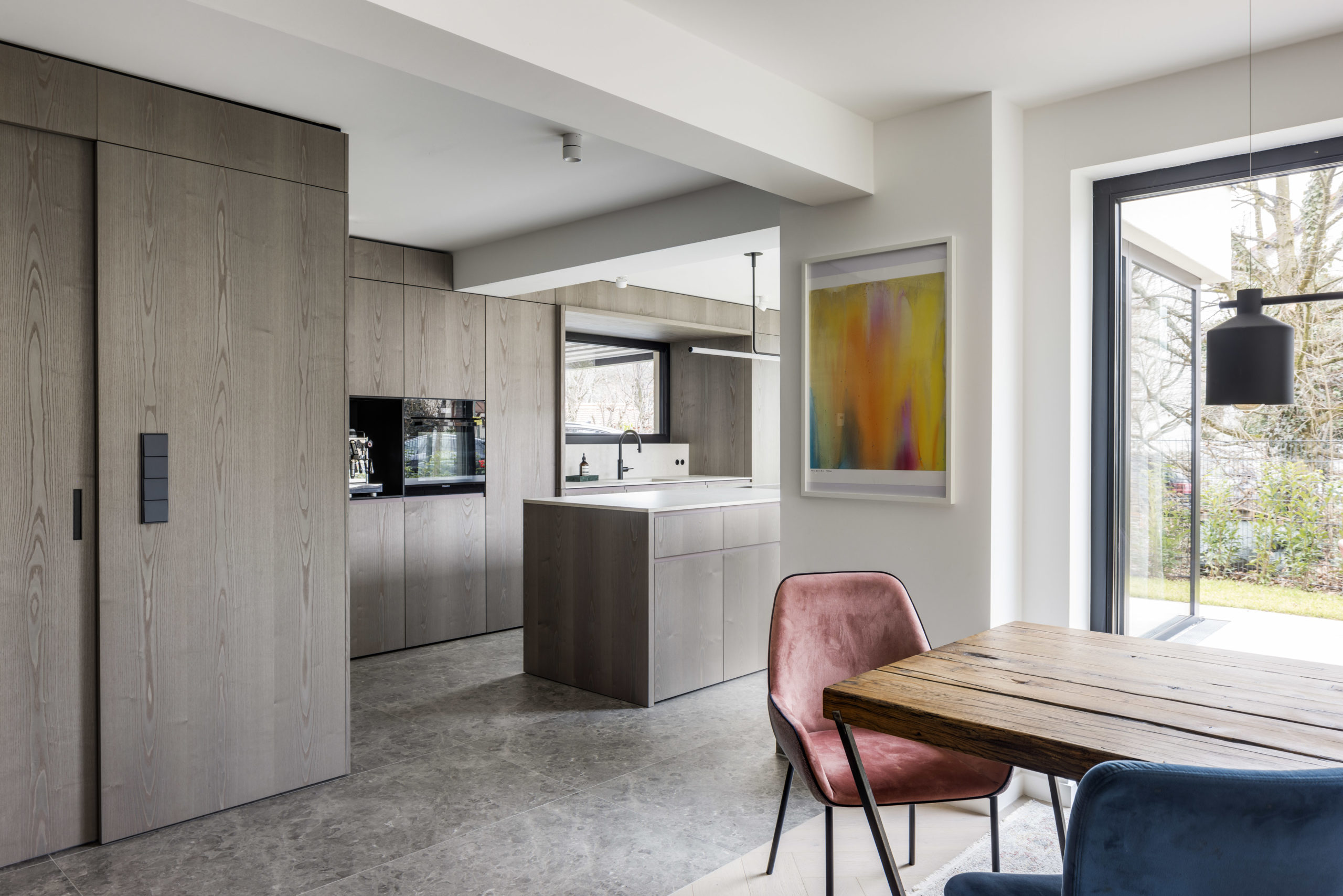 Moderne Küche mit grauen Holzfronten, maßgefertigter Einbau und offenem Essbereich