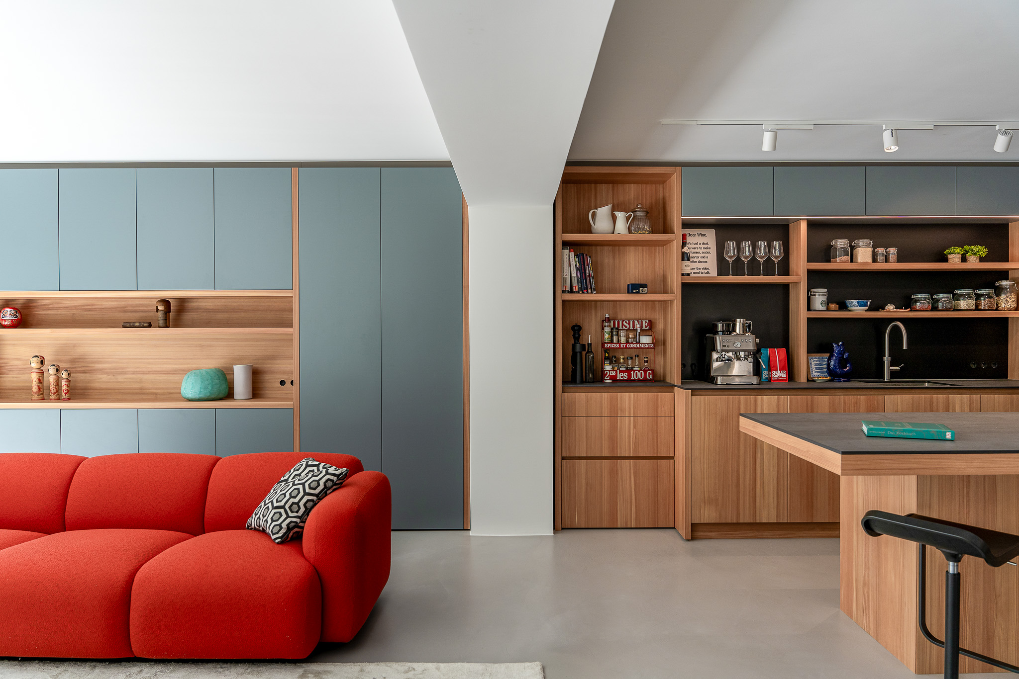 Offene Küche in Schwabing mit Wohnzimmerwand, rotem Sofa und integrierter Kaffeenische aus Holz und farbigen Fronten