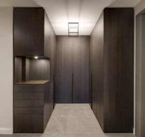 Moderner maßgefertigter Einbauschrank in dunkler Holzoptik mit offenem Regal und Beleuchtung