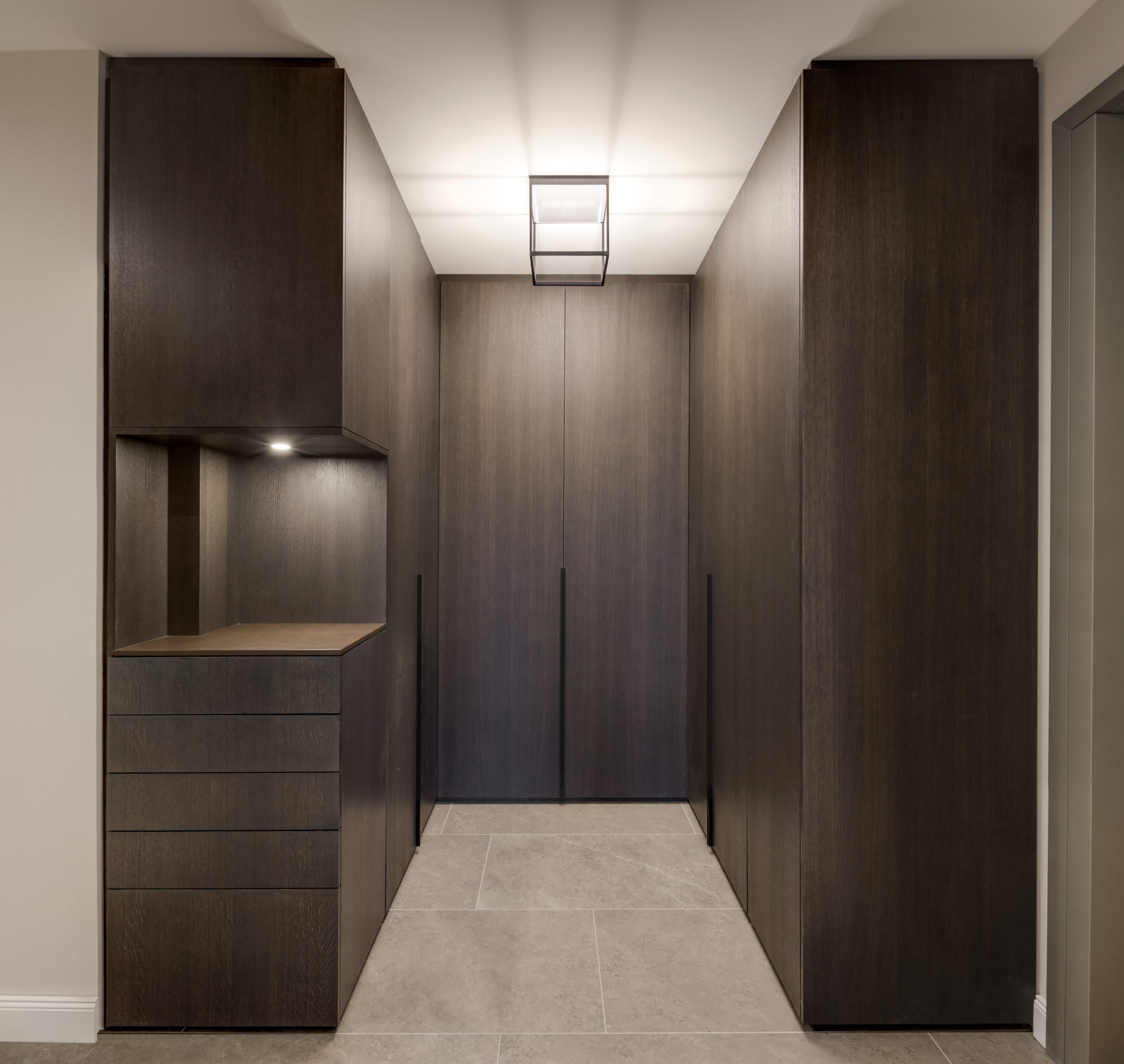 Moderner maßgefertigter Einbauschrank in dunkler Holzoptik mit offenem Regal und Beleuchtung