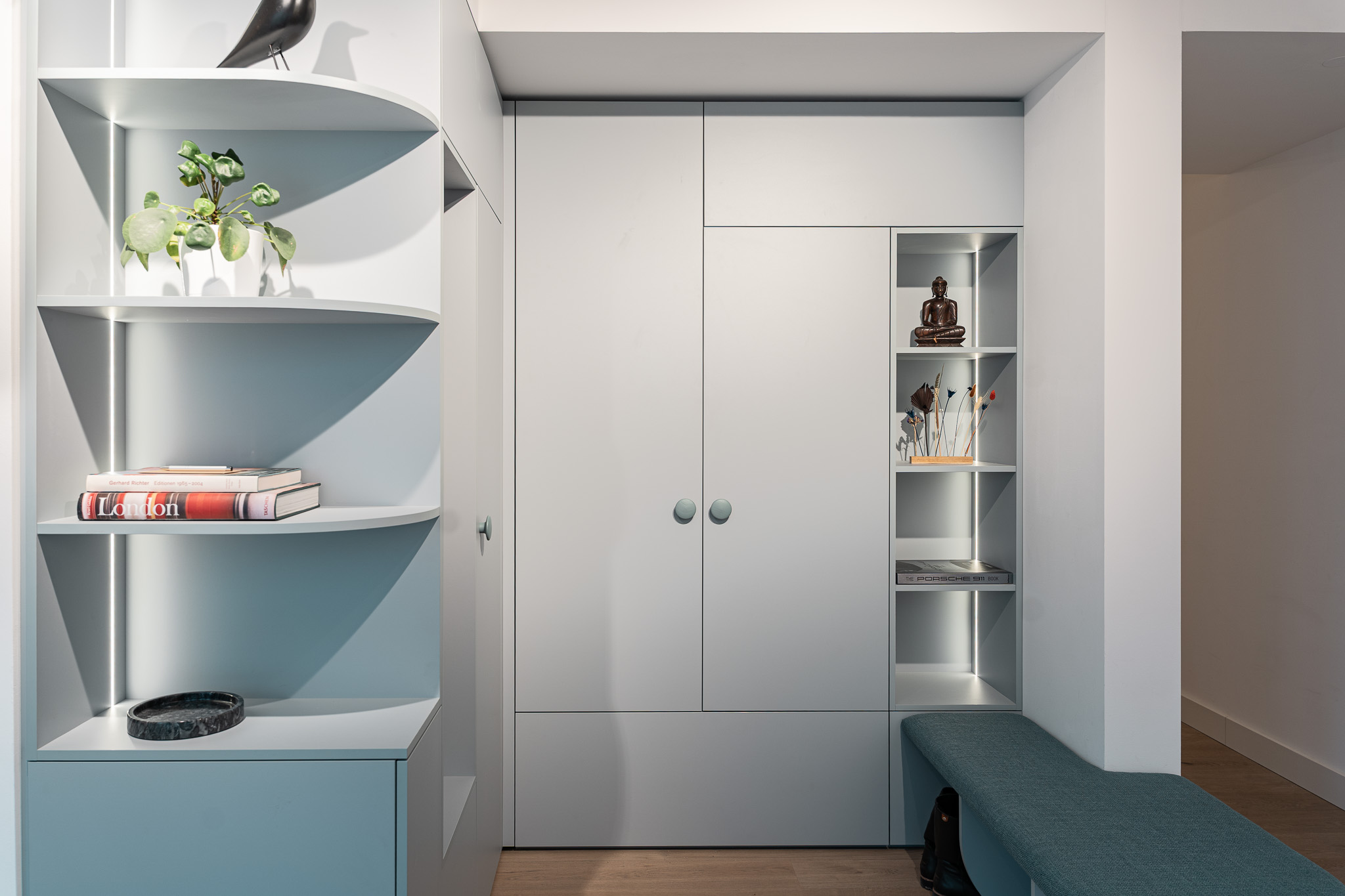 Moderner, maßgefertigter Garderobenschrank in heller Ausführung mit offenem Regal, Sitzbank und dekorativer Beleuchtung.