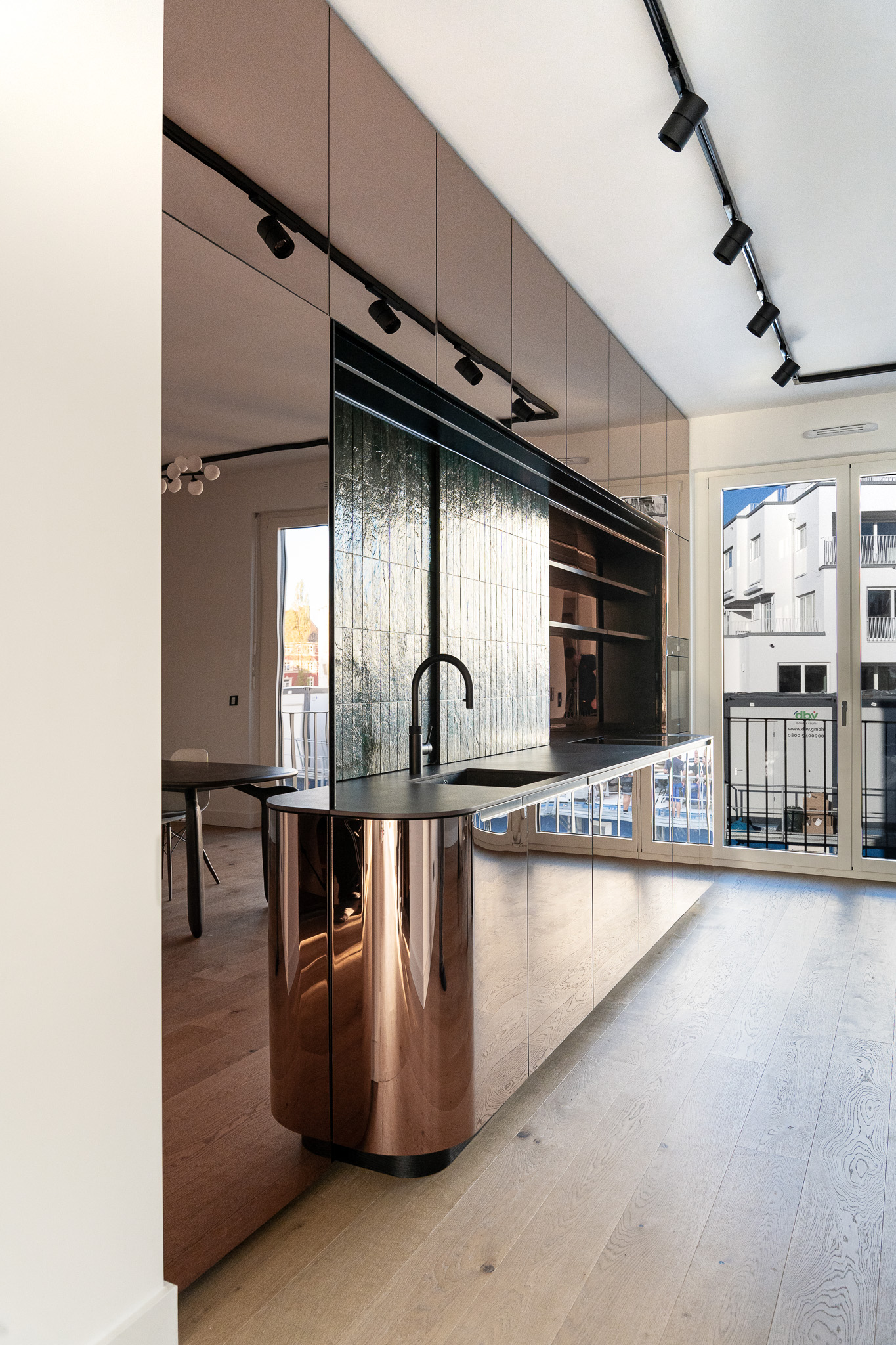 Moderne Designküche mit grüner Fliesenrückwand und spiegelnden Schrankfronten