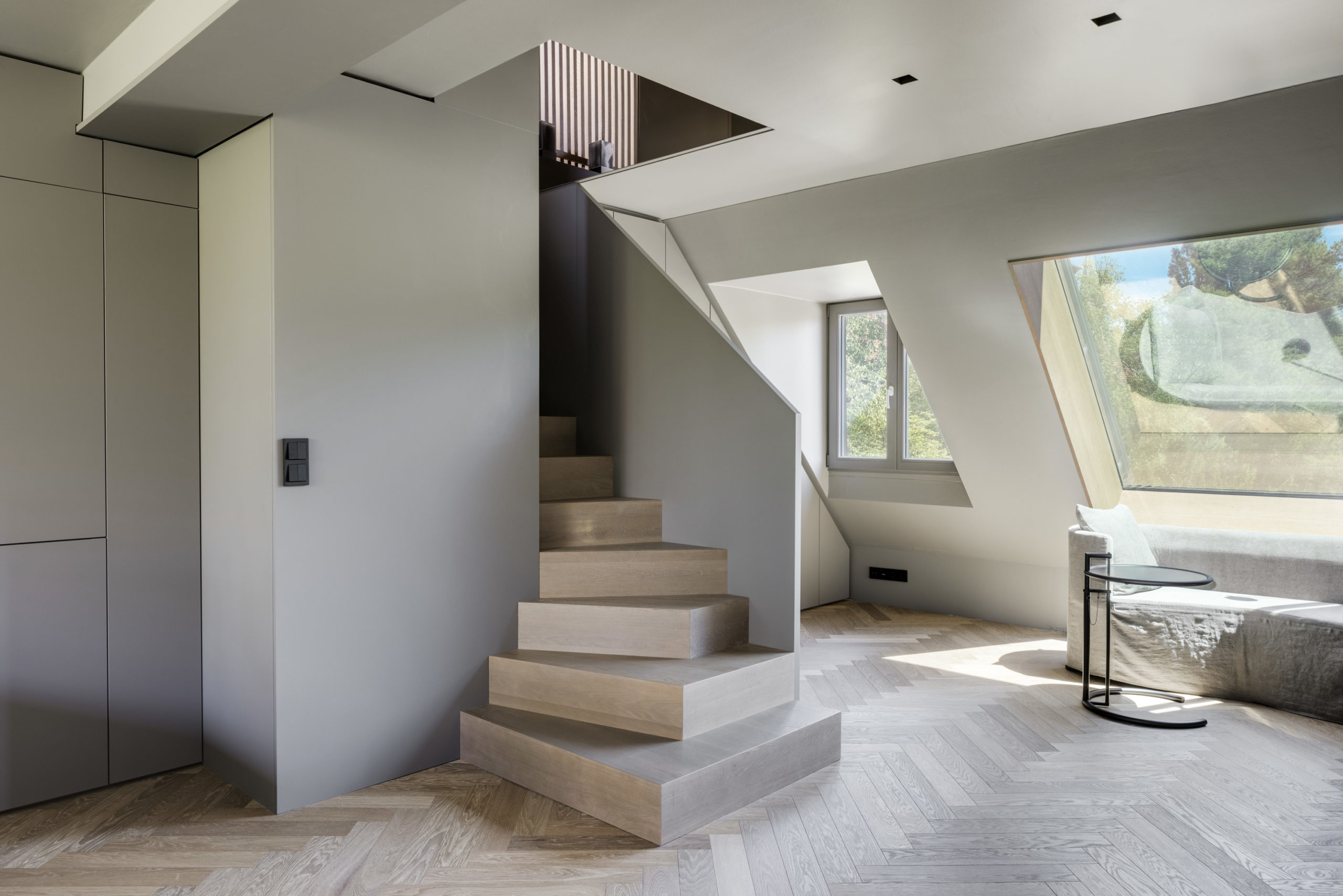 Moderne Innentreppe aus Holz mit grauen Wänden in minimalistischem Wohnraum