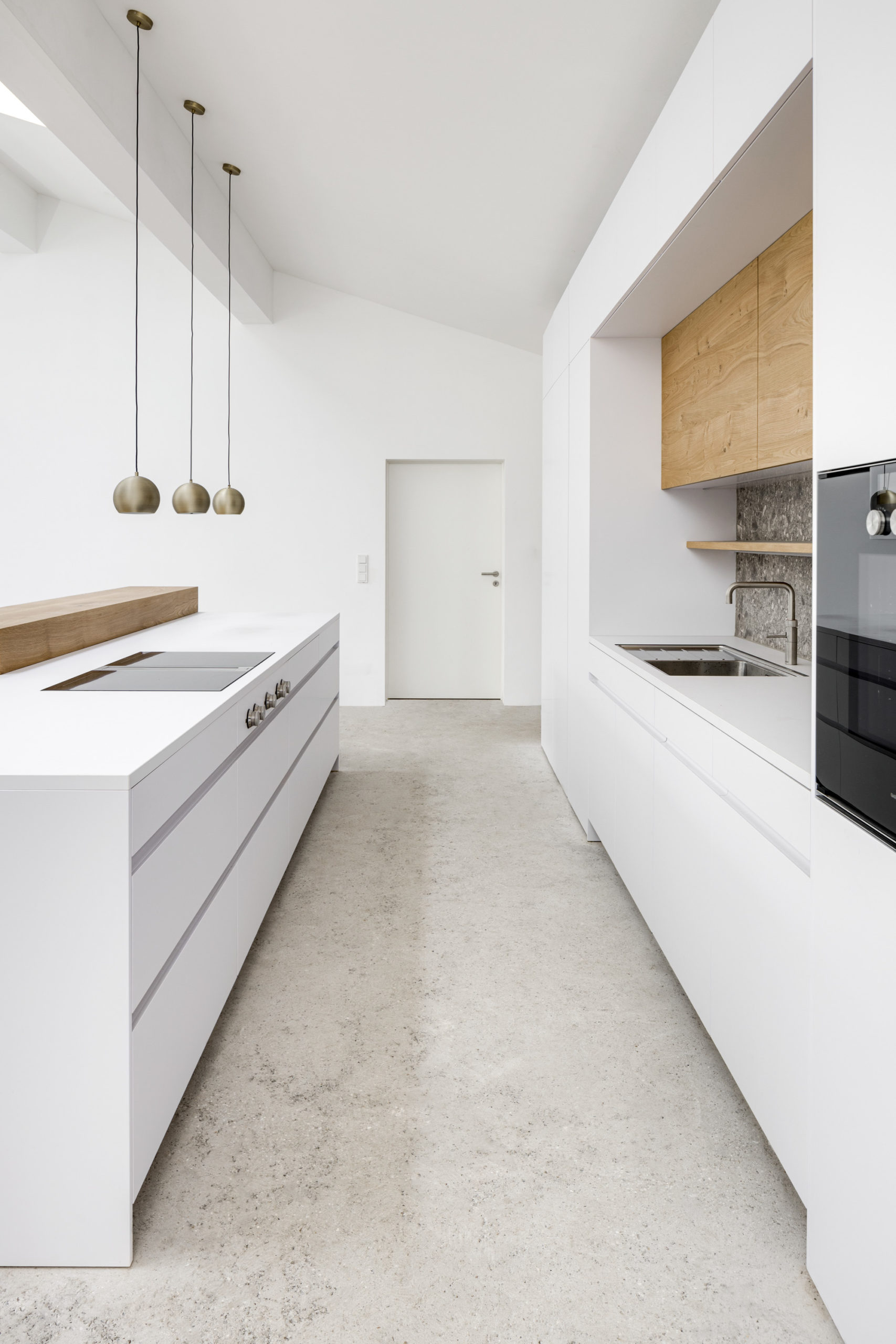 Moderne weiße Küche mit Terazzo-Arbeitsplatte und Kochinsel mit Griffmulde