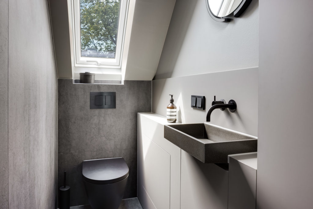 Modernes Gäste-WC mit Dachfenster, grauen Fliesen und schwarzer Armatur
