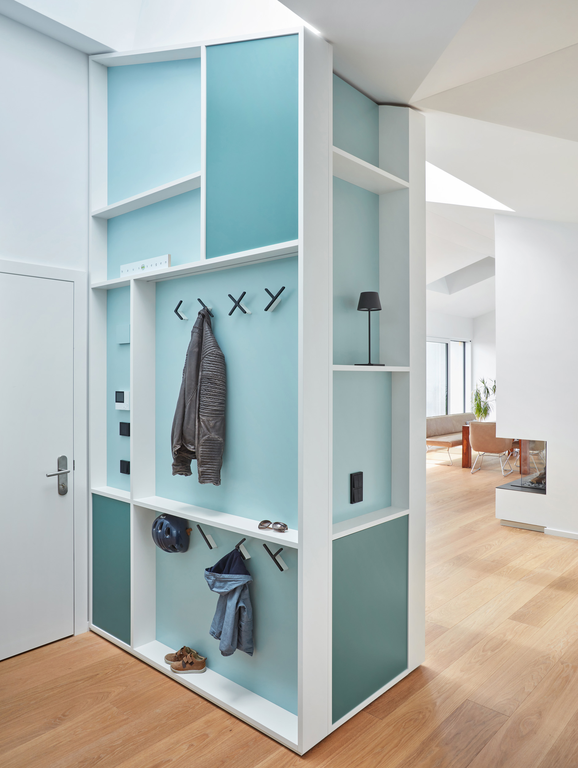 Flur mit maßgefertigter Garderobe und Blick auf Wohnbereich mit Kamin
