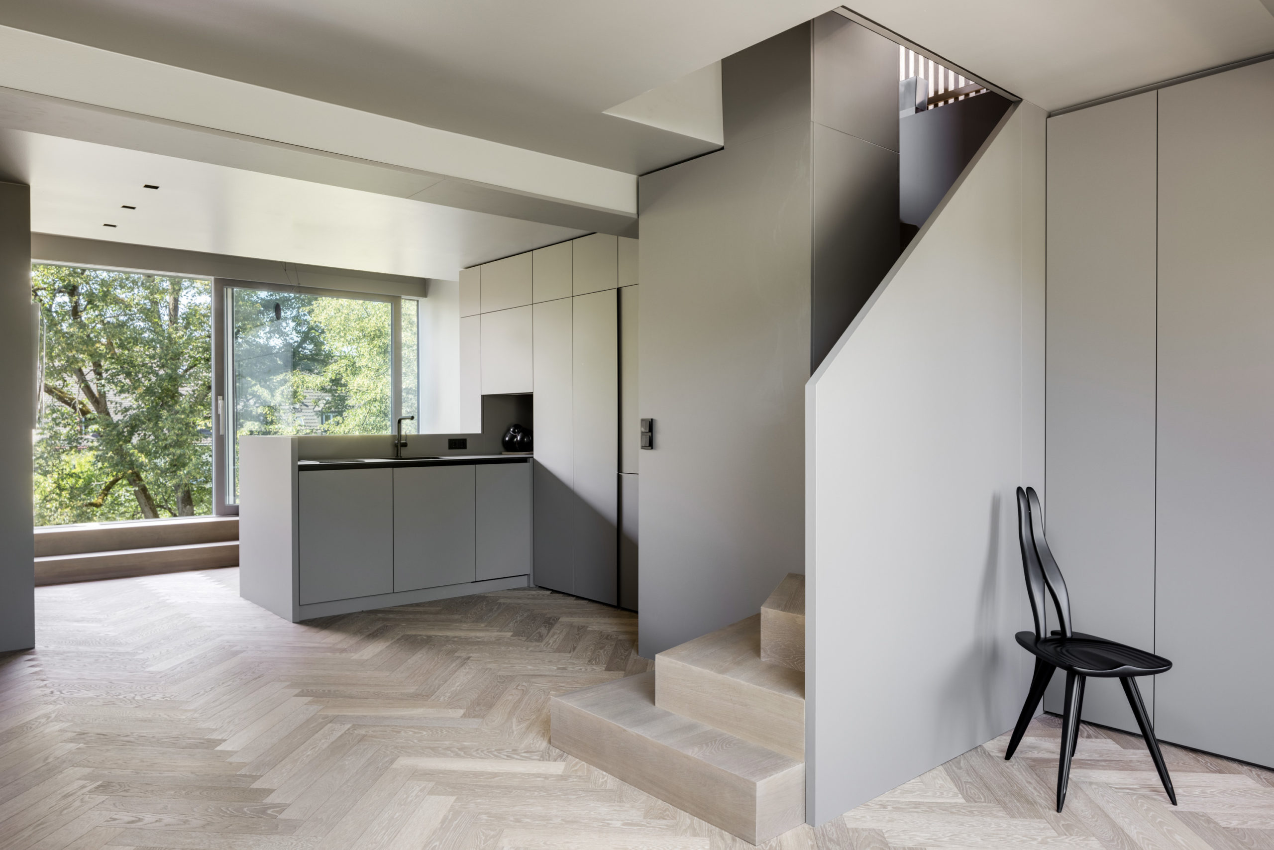 Offene Küche mit hellem Holzboden und moderner Design-Treppe