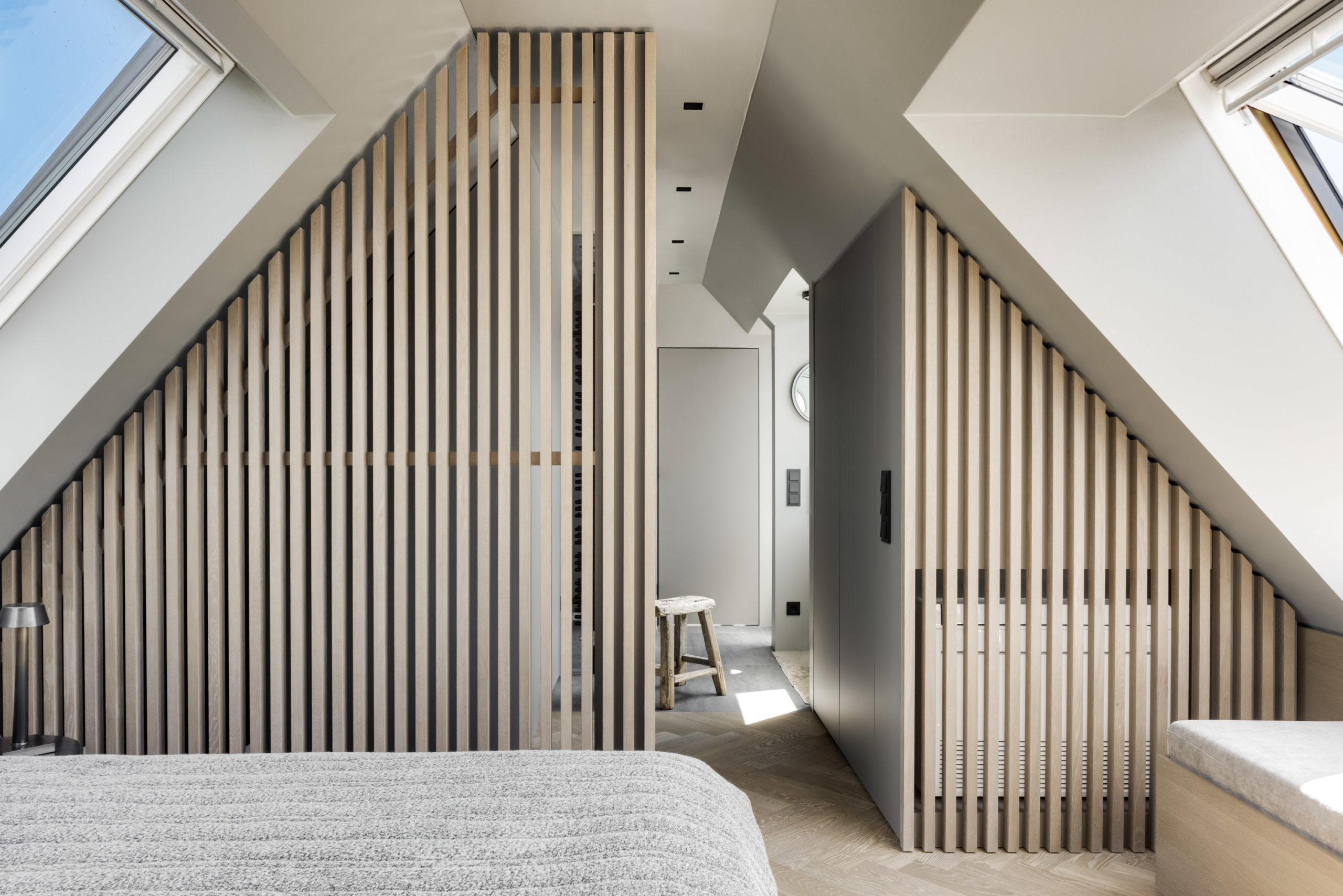 Modernes Schlafzimmer mit Holzlamellen-Trennwand und Dachfenstern