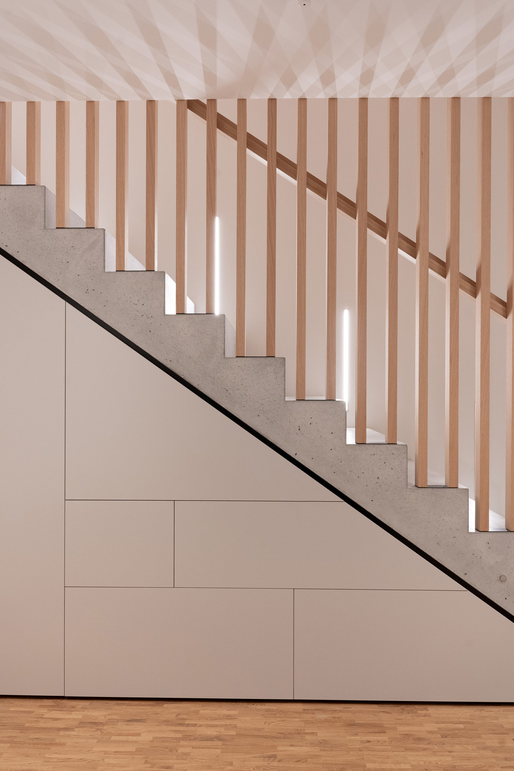 Betontreppe mit integriertem Stauraum und vertikalen Lamellen als Absturzsicherung im zeitgemäßen Innenausbau
