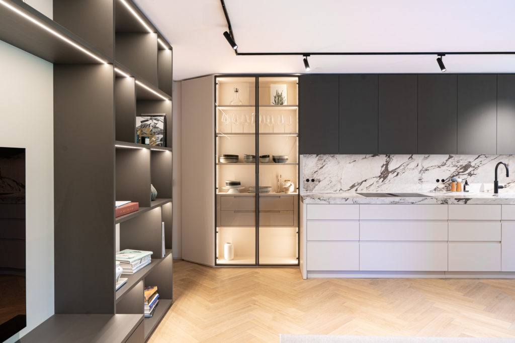 Offene Wohnwand mit integrierter Glasvitrine im Küchenbereich, Innenausbau München