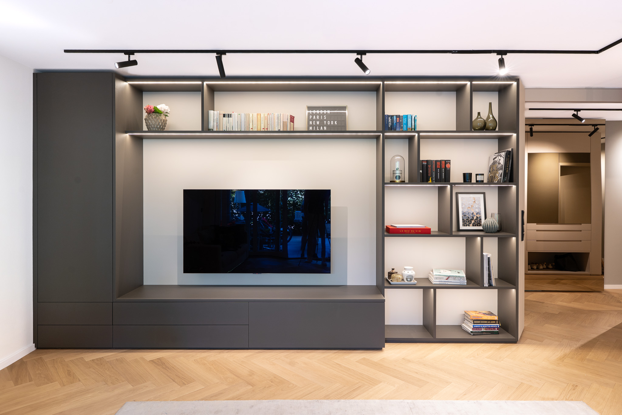 Maßgefertigte Wohnwand im Wohnzimmer mit integriertem TV und Regal in modernem Innenausbau, München