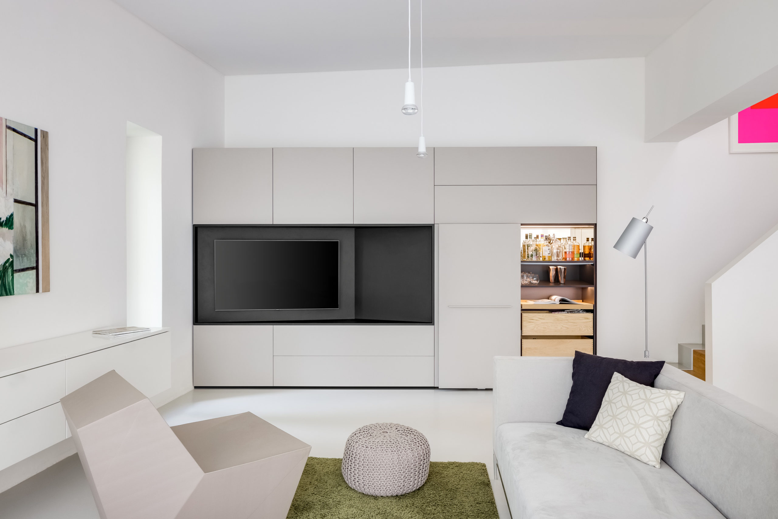 Wohnzimmer mit Einbauschrank, geöffnetem Barfach und integrierter Beleuchtung