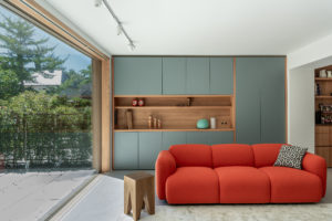 Offene Küche in Schwabing mit Wohnzimmerwand, rotem Sofa und integrierter Kaffeenische aus Holz und farbigen Fronten