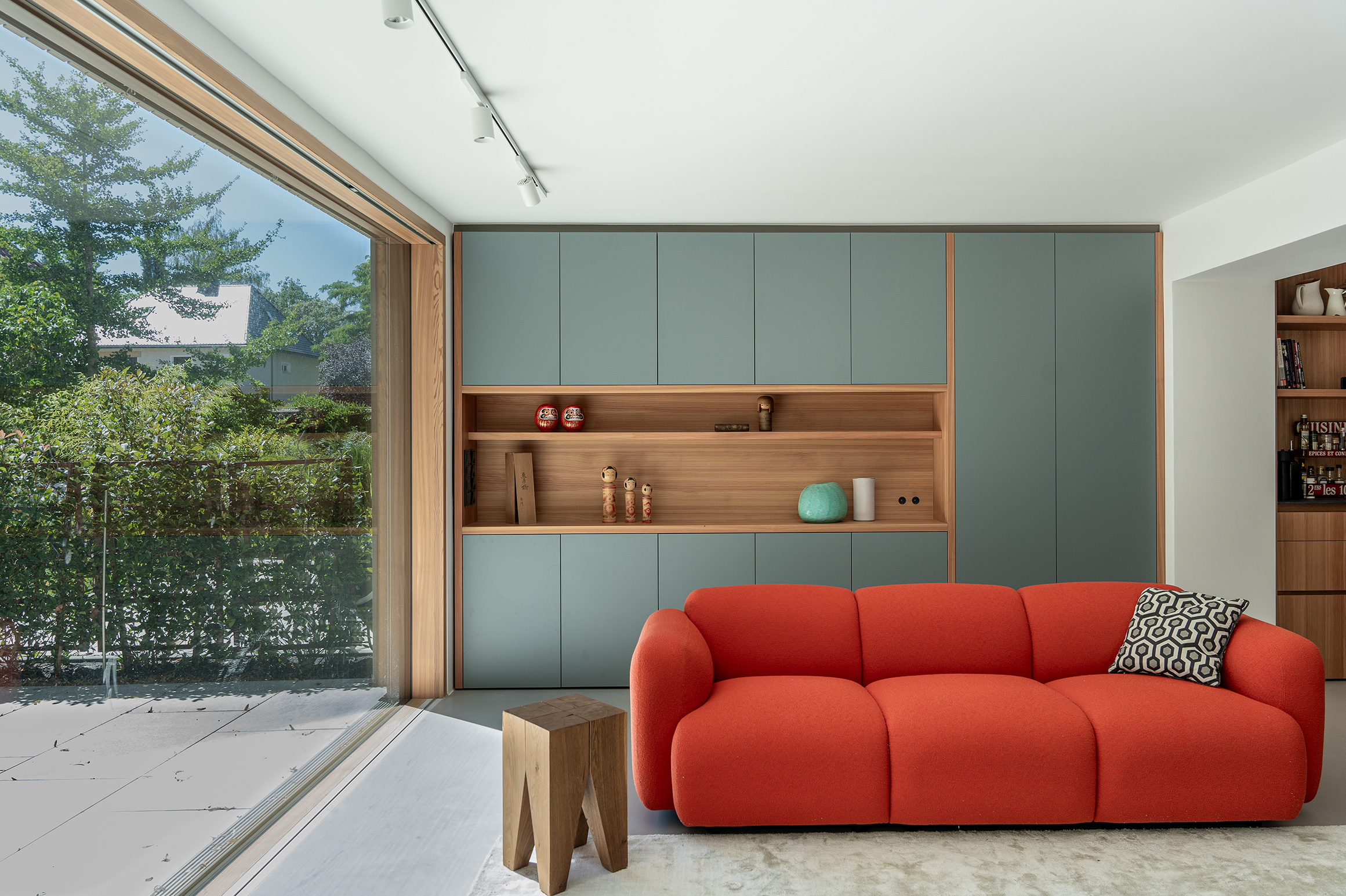 Offene Küche in Schwabing mit Wohnzimmerwand, rotem Sofa und integrierter Kaffeenische aus Holz und farbigen Fronten