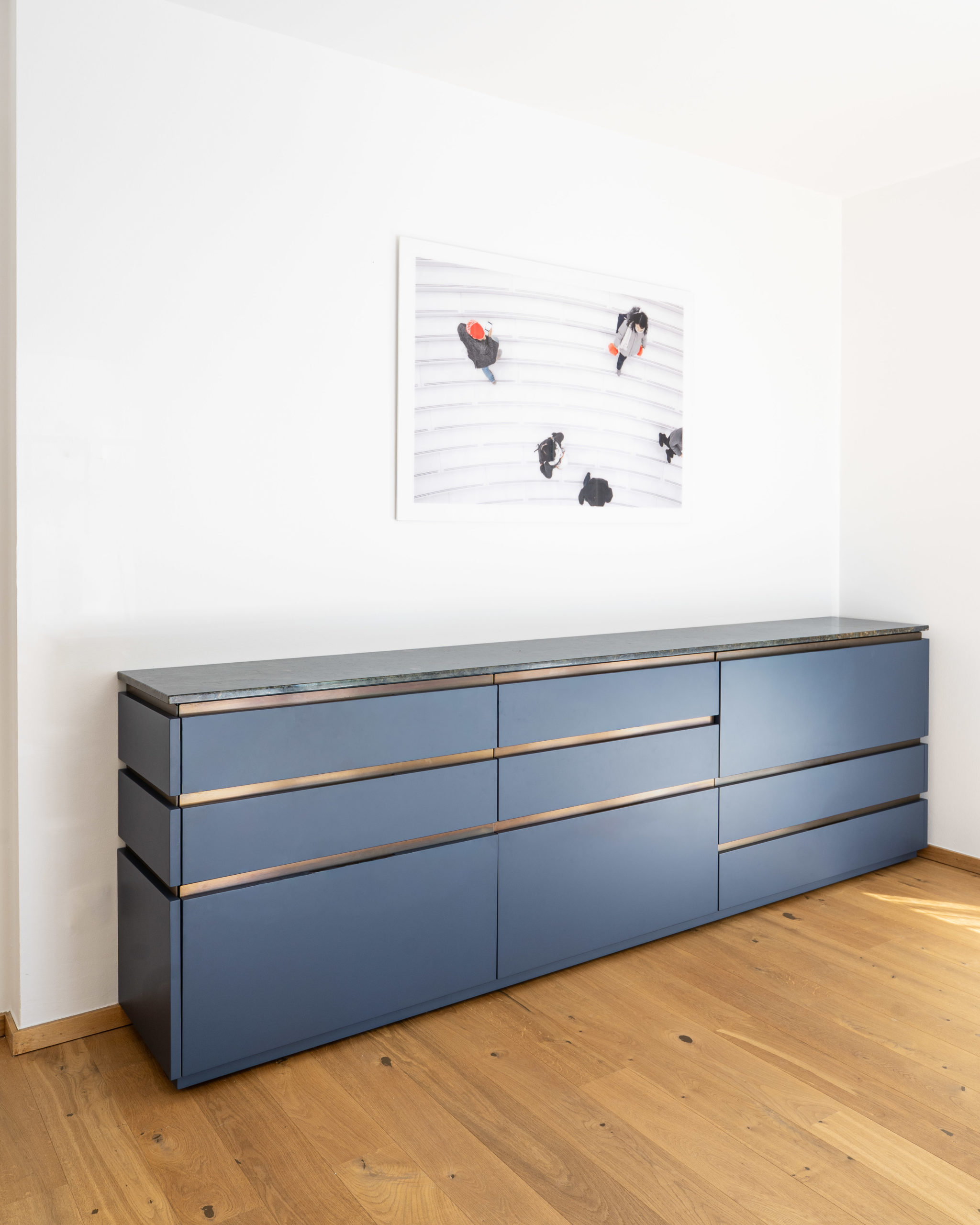 Modernes Design-Sideboard in Blau mit Holzakzenten und edler Natursteinplatte, minimalistischer Innenausbau.