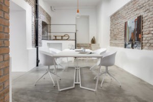 Industrieller Meetingraum mit Backsteinwand, weißen Flächen und modernem Tischdesign von Studio Moura